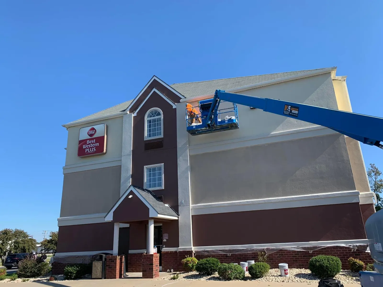 Three-story hotel exterior with a boom lift raised to the upper wall