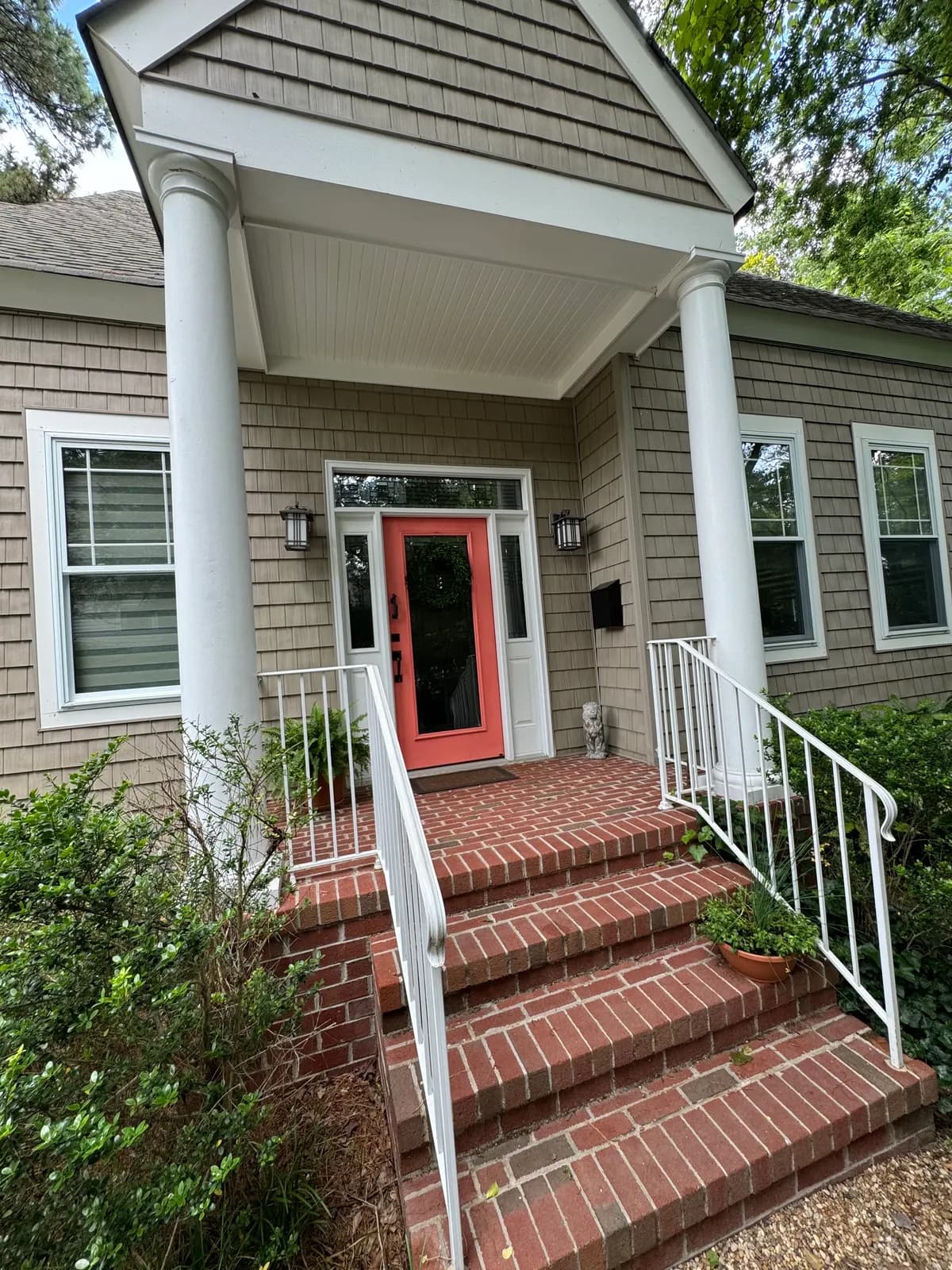 Front porch with white columns, gray siding and a coral front door