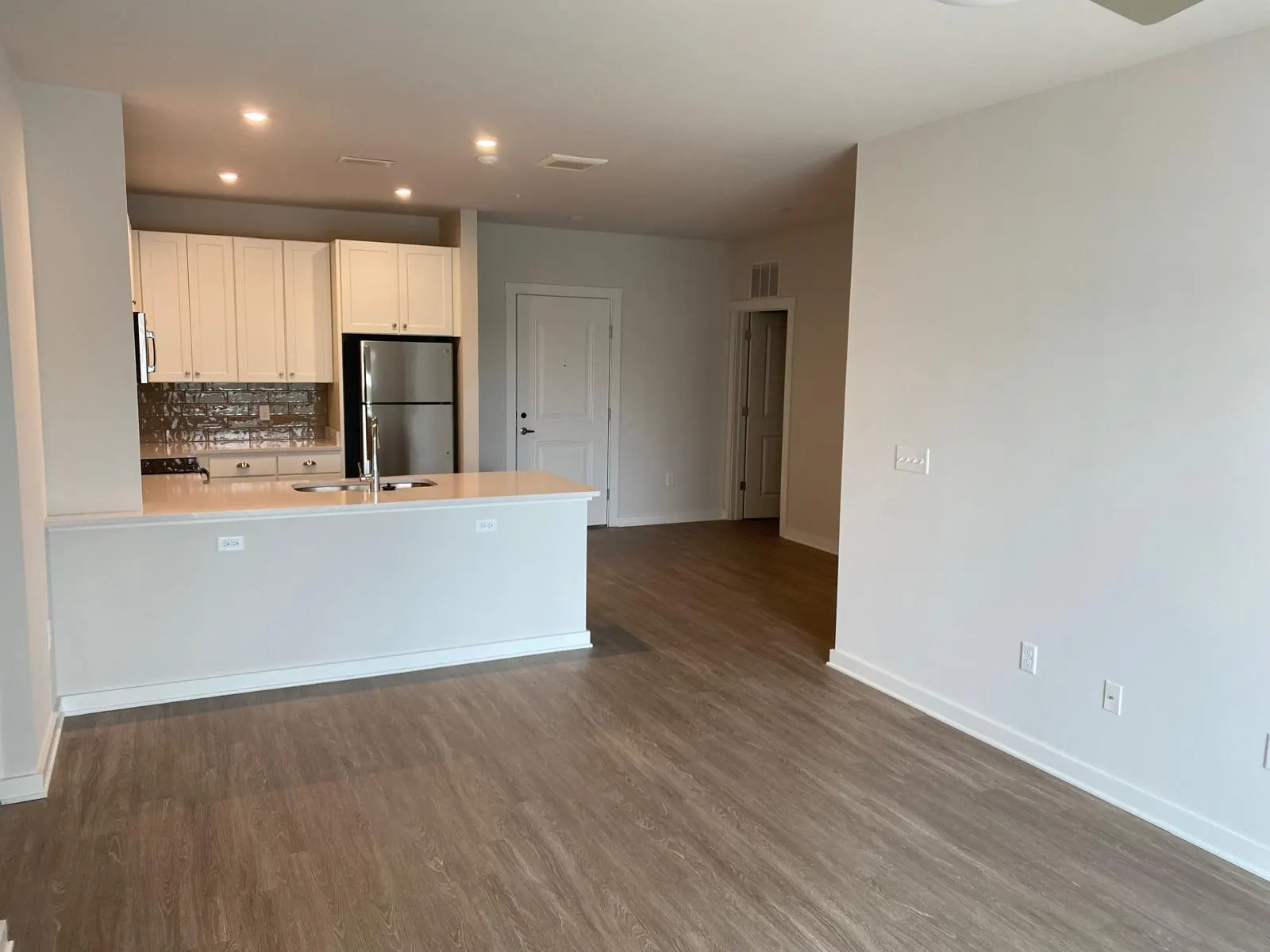 Open-plan apartment with white walls, wood floors and a kitchen