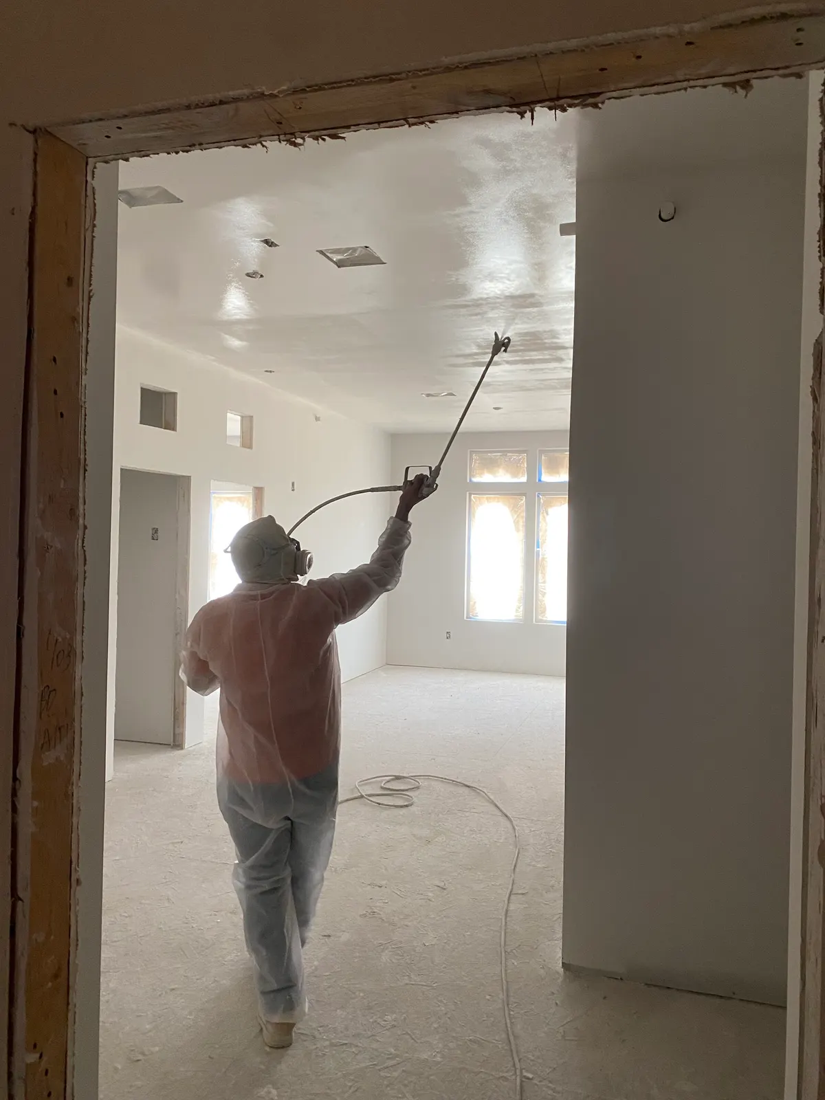 Painter spraying a ceiling white in an empty room